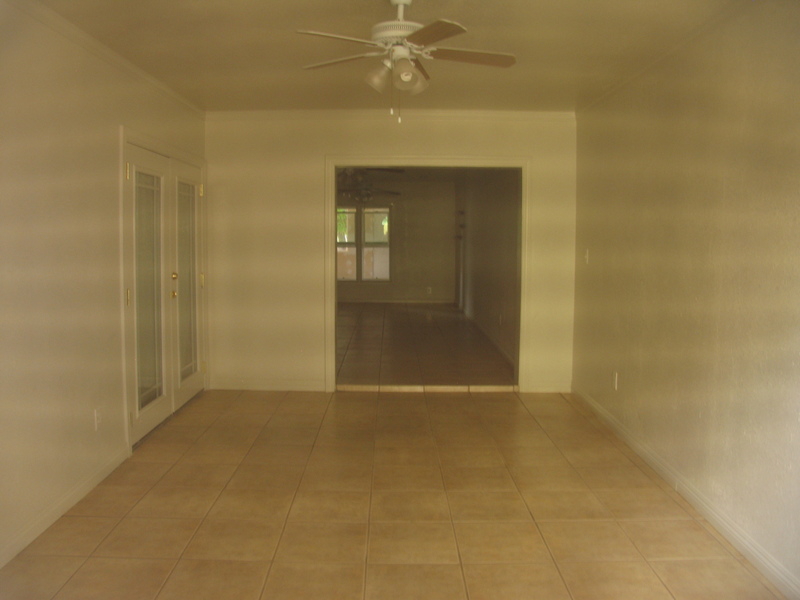 Picture taken from back of house. This is the diningroom, I guess, and you can see french doors on the west leading to (kitchen?). In the background is the livingroom and front window.