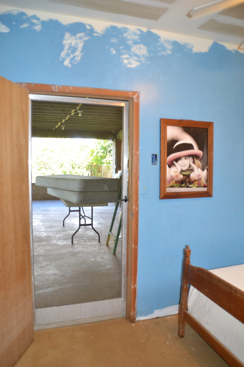 Here is the inside of the door looking out onto the lanai. We have a six-foot banquet table available for your room, but right now it has mattresses on it. Feel free to move all the furniture around to your liking. You can also paint or put things on the walls.