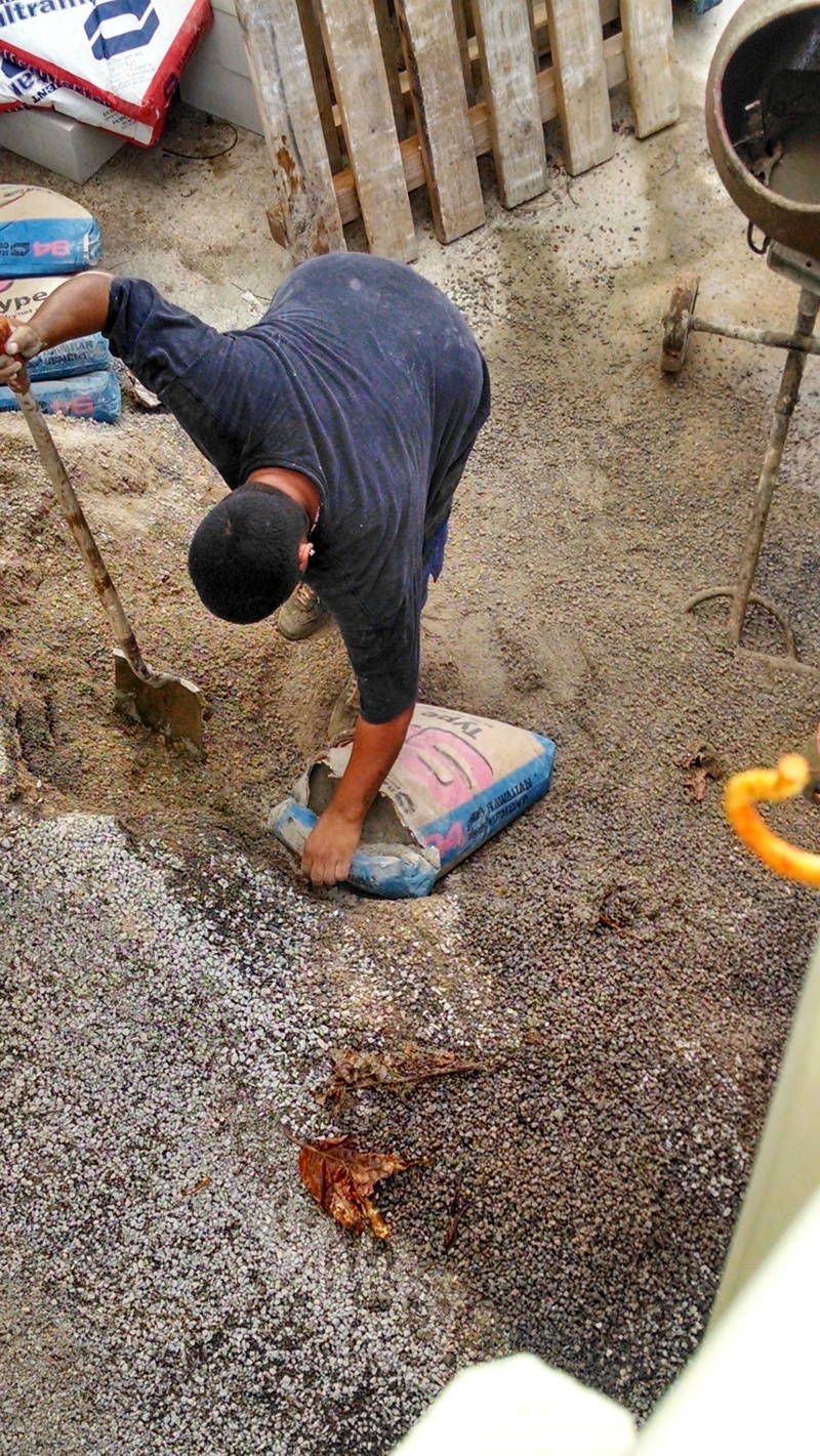 Breaking open a bag of cement to mix with the sand and gravel.