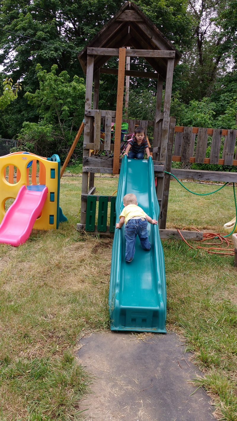 Austin uses the slide the way every self-respecting child has ever done. Calvin looks on.