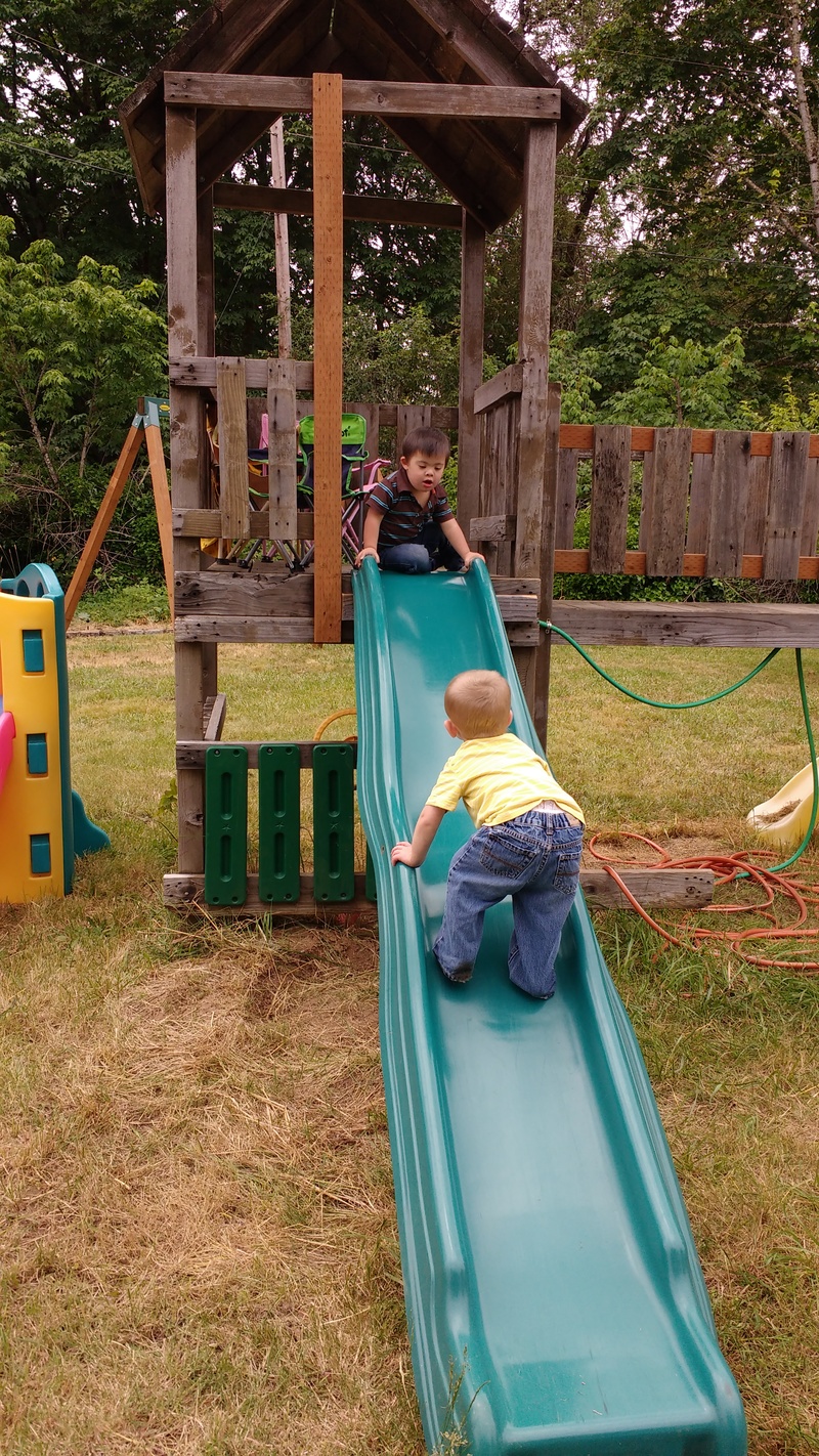 Austin uses the slide the way every self-respecting child has ever done. Calvin looks on.