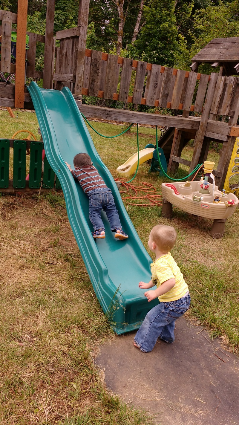 Calvin goes down the slide. Austin waits at the bottom.