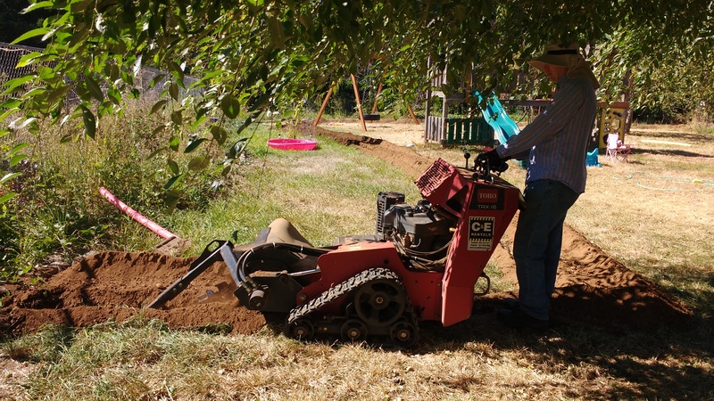 Joseph operating the trencher we rented. We will install water pipes around the property.