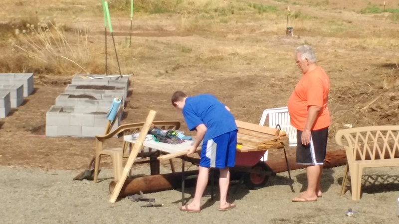 Raised bed garden cells in the background. Isaac and Don working in the foreground, removing nails. Boy, Don has put on a lot of weight.